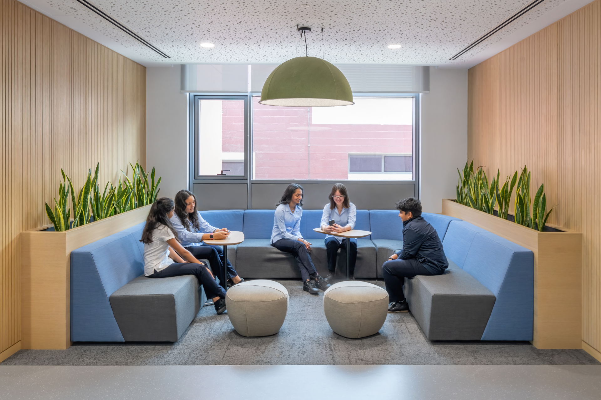 Students in a Dubai College breakout space with an acoustic pendant light
